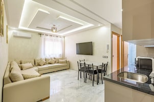 Una sala de estar moderna con sofá, mesa de comedor y televisor.