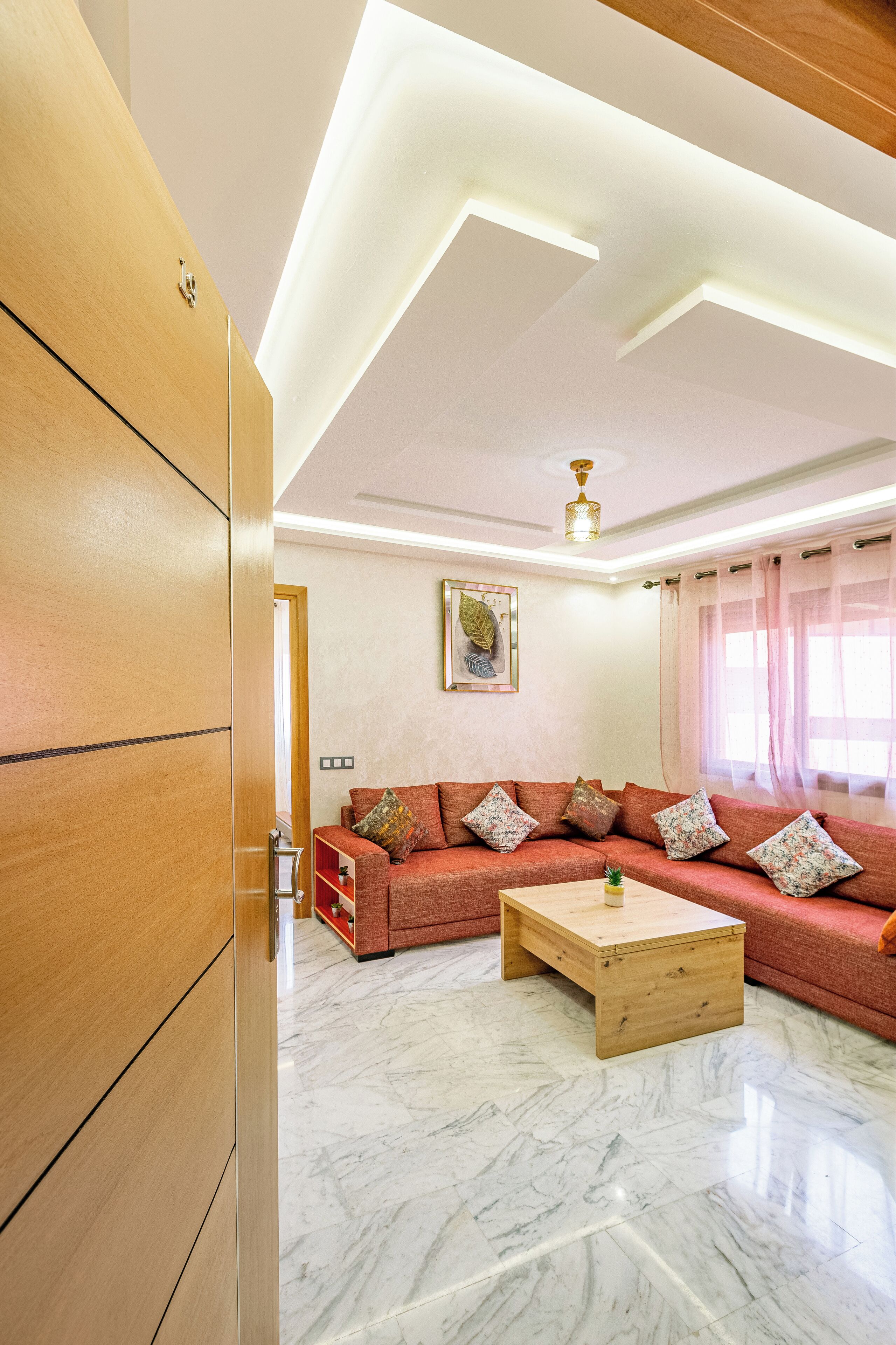 Una sala de estar con un aparador de madera, un conjunto de sofá rojo, una mesa de centro de madera y una lámpara en el techo.