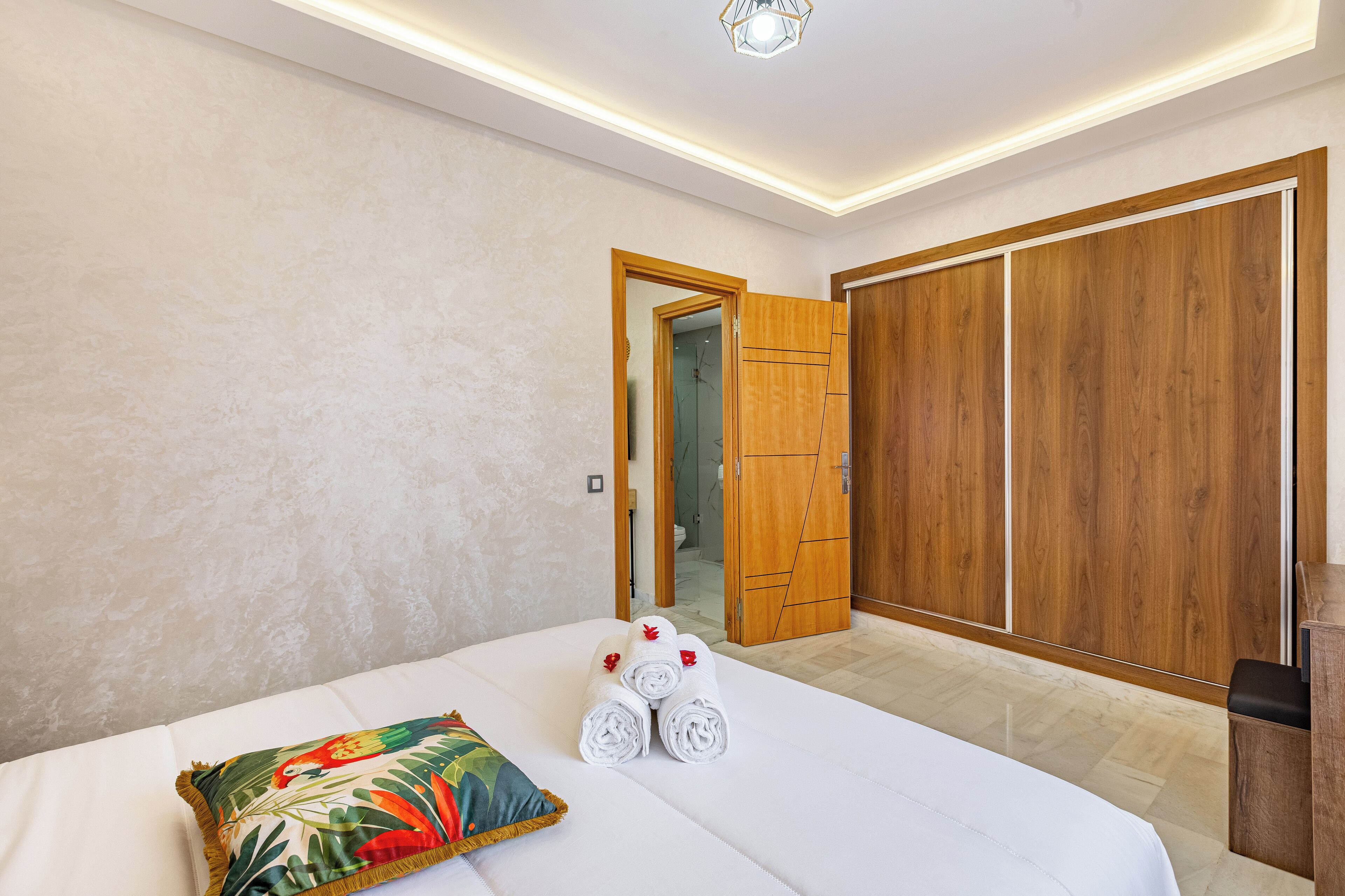 A hotel room with a bed, a pillow, and a set of towels.
