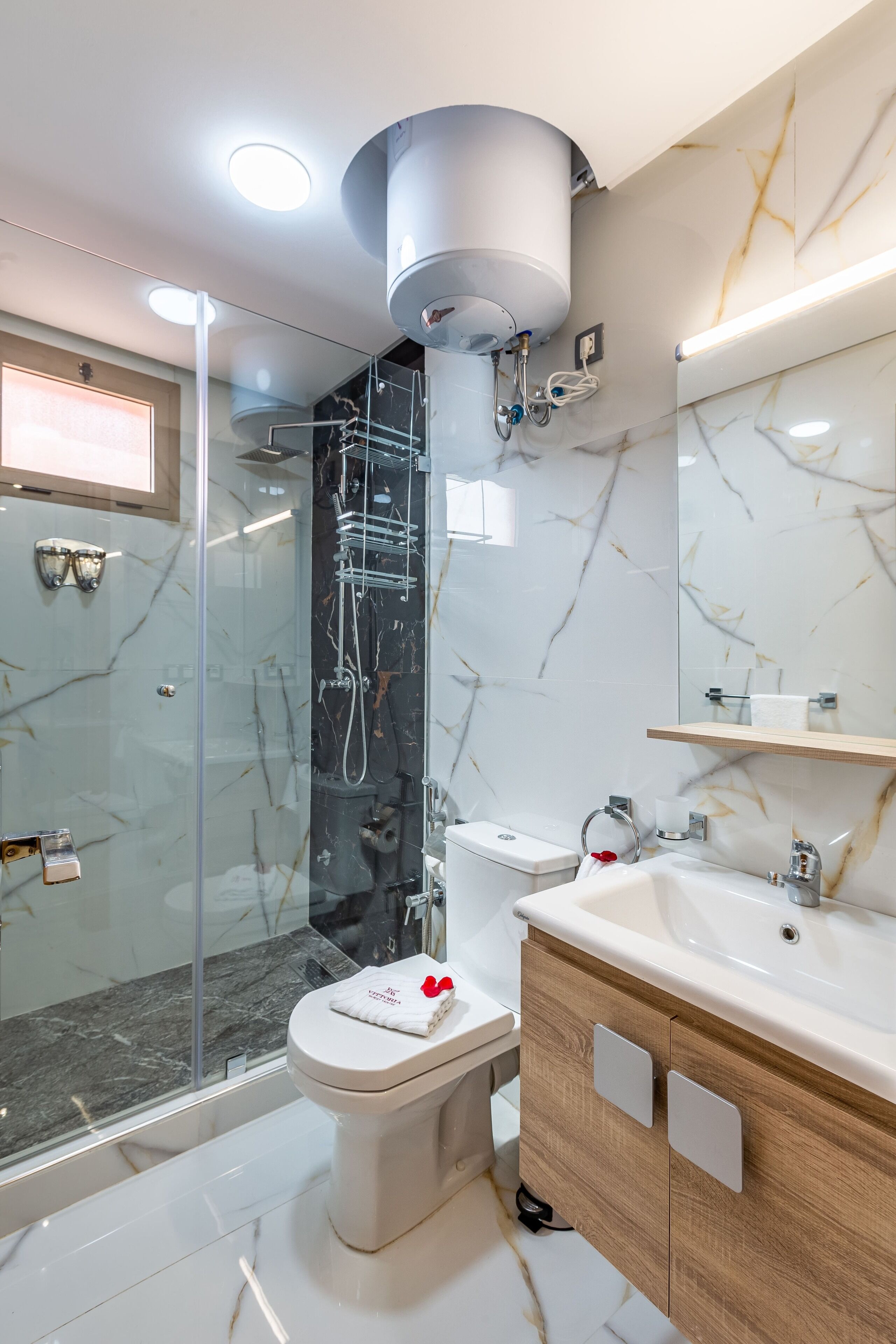 A modern bathroom with a glass-enclosed shower, a white toilet, and a wooden vanity with a sink.