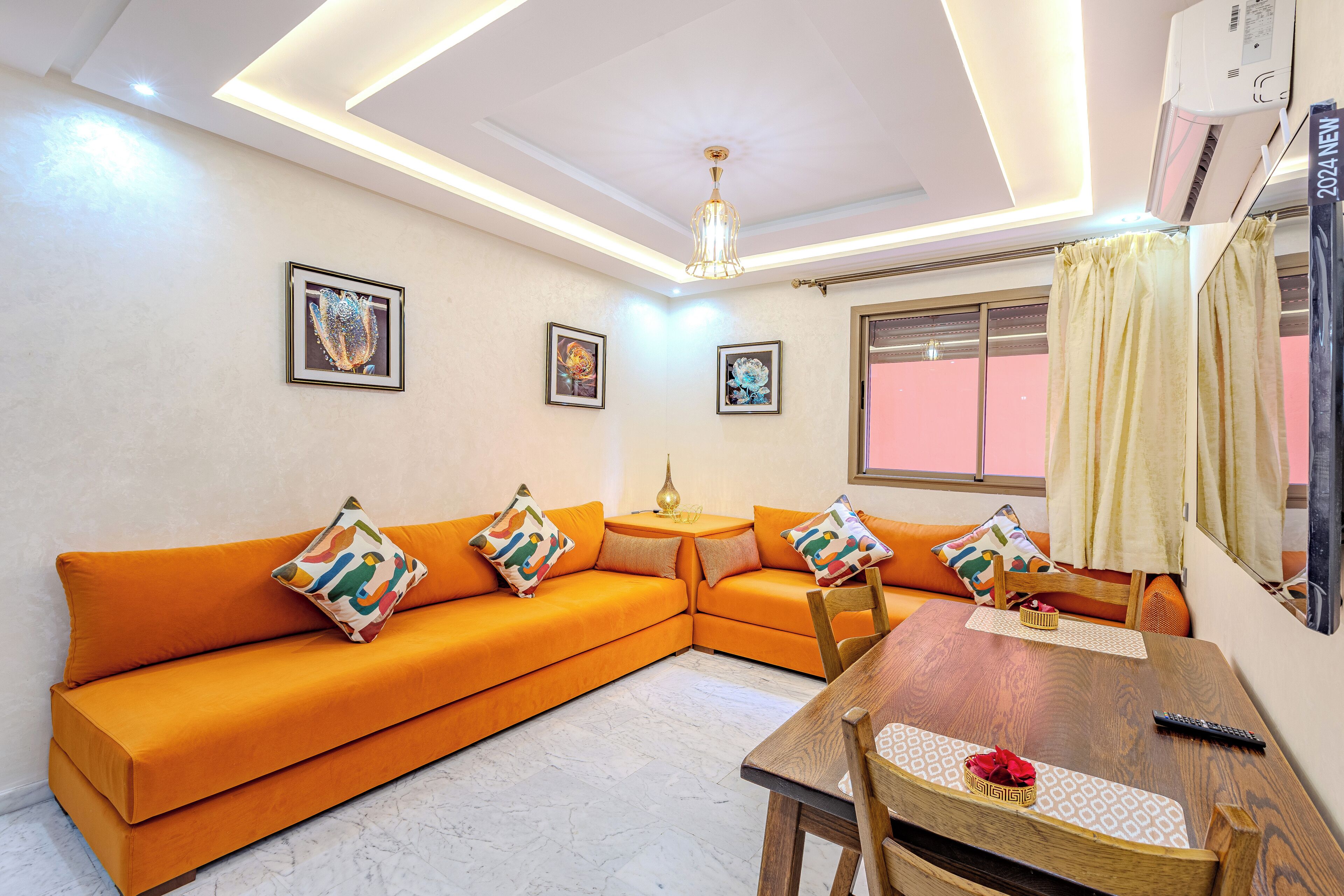 A modern living room with a sectional sofa, a dining table, and a ceiling light fixture.
