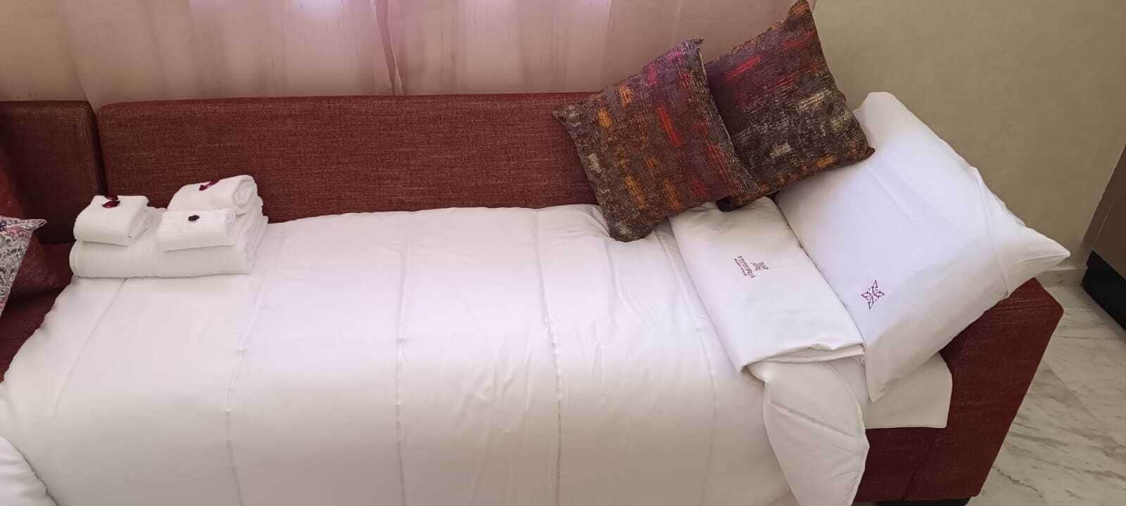 A neatly made bed with white linens and a red headboard.