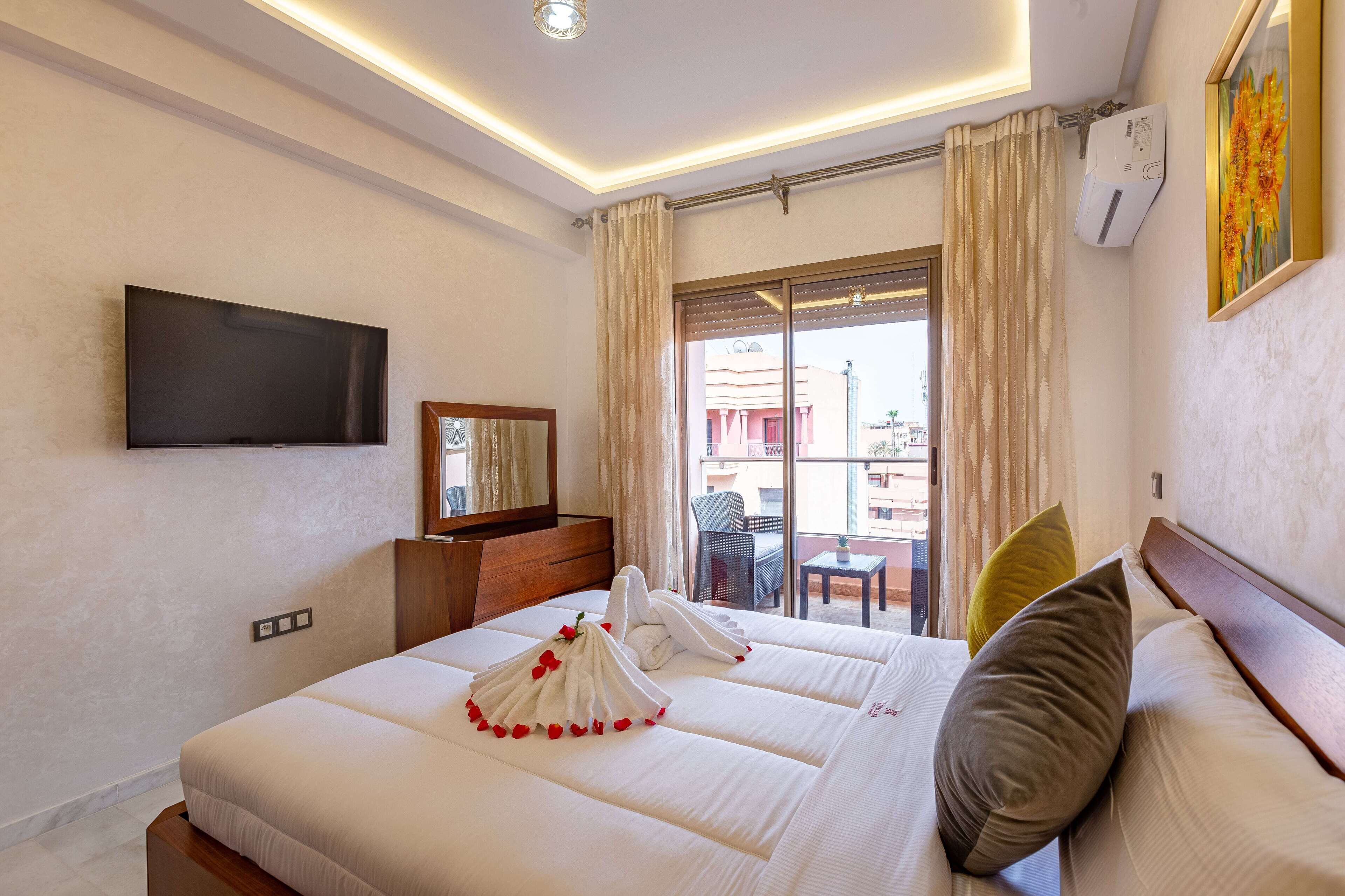Habitación de hotel con una cama grande, un televisor de pantalla plana, un balcón con vistas y aire acondicionado instalado.