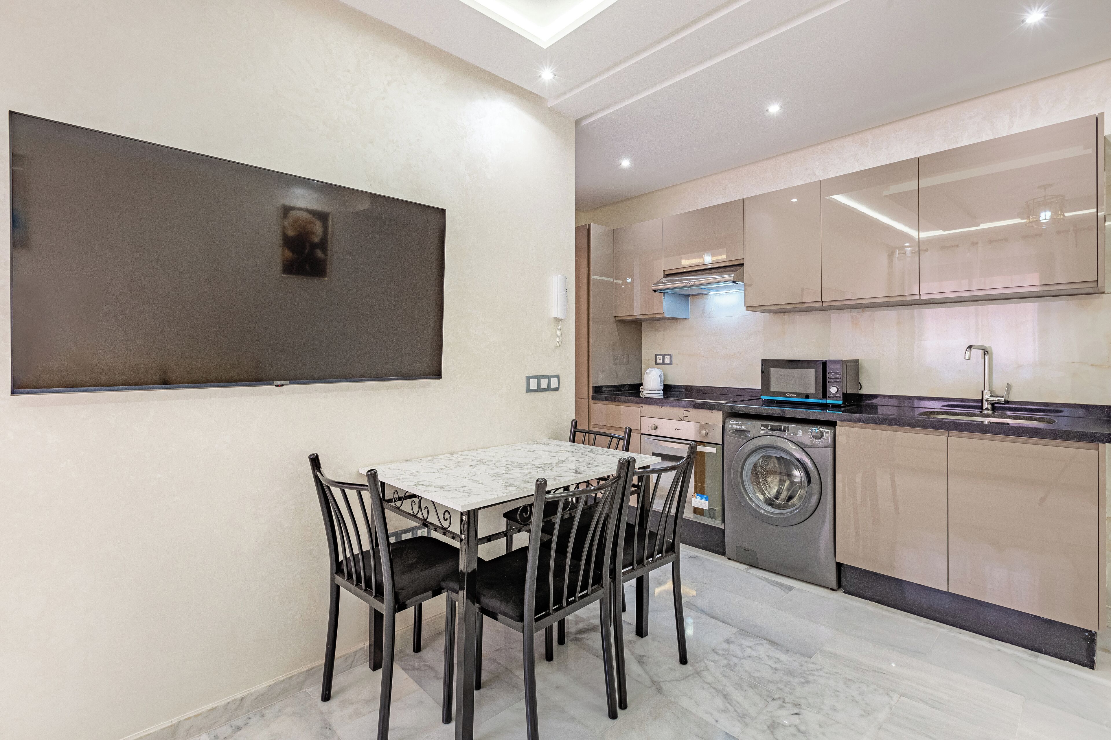 Una cocina moderna con comedor, que incluye una mesa y sillas de mármol, una lavadora y un armario grande.