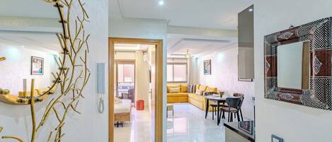 A modern living room with a sofa, a dining table, and a decorative mirror.