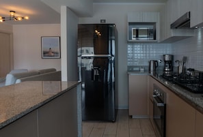 Et moderne køkken med et rustfrit stål køleskab, indbygget mikroovn og granitbordplader.