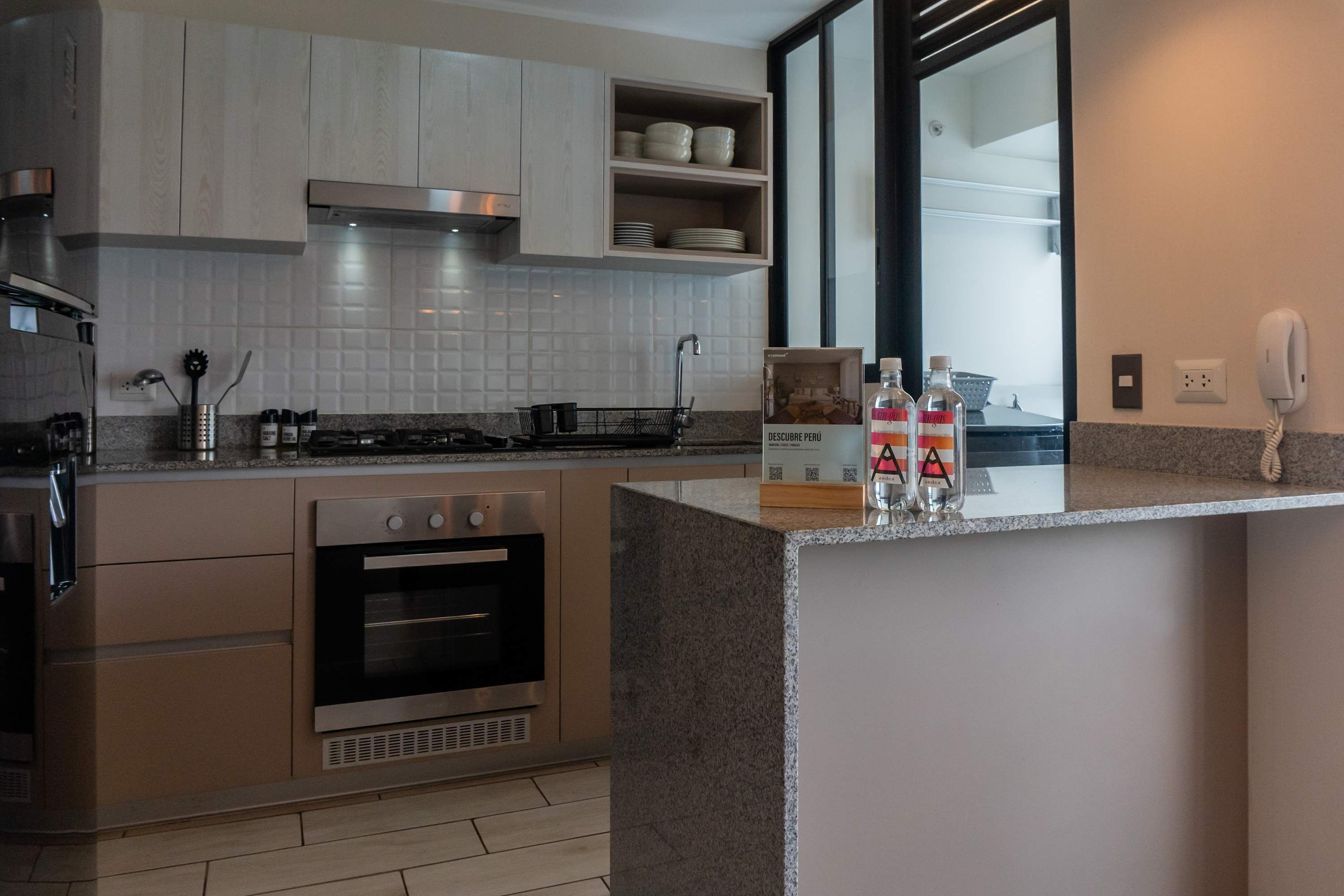 Une cuisine moderne dotée d’appareils électroménagers intégrés, d’un plan de travail avec un évier et d’un pare-feu en miroir.