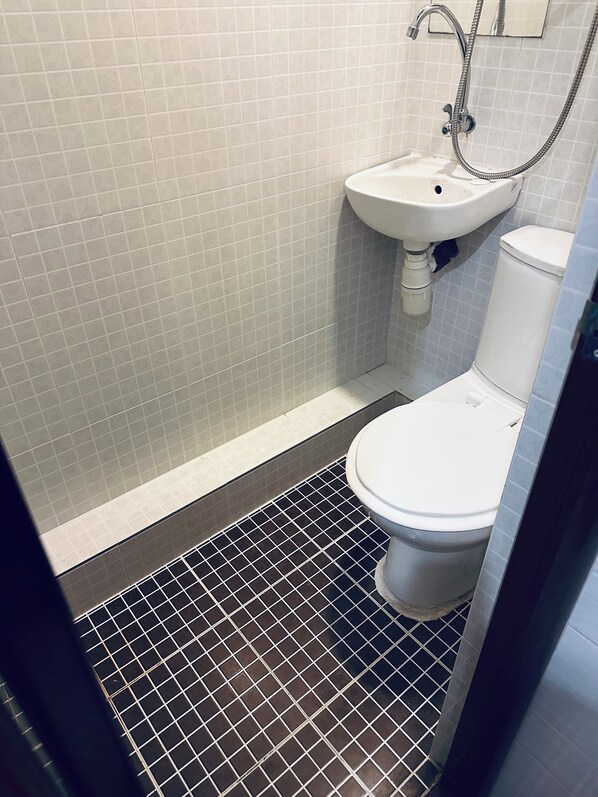 Un baño pequeño con inodoro, lavamanos y ducha.