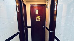 Un pasillo con piso de baldosas blanco y negro, una puerta de madera con un número y un pequeño adorno en la puerta.