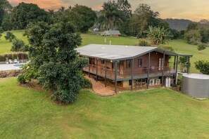 A wooden cabin with a deck, surrounded by lush greenery and a large tree. - The Hideaway - Chic Farmhouse, 15min to Beaches (Sunshine Coast Hinterland)
