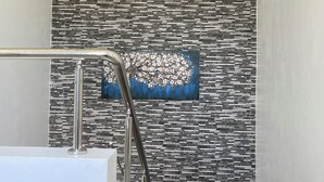 A bathroom with a modern design, featuring a textured wall and a painting of a tree. - Level Suites #3 Premium Suite (Sosúa)
