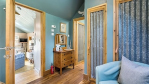 A room with a wooden floor, a blue sofa, a wooden dresser, and a mirror. - The Birdhouse - a luxurious cottage with log burner in the Highlands (Applecross Strathcarron)