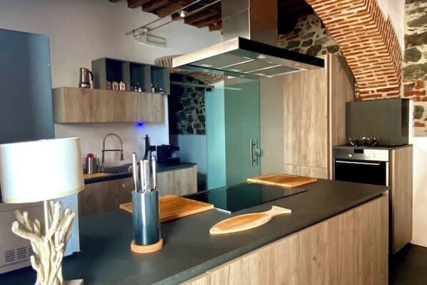 A modern kitchen with a central island, built-in appliances, and a stone accent wall.