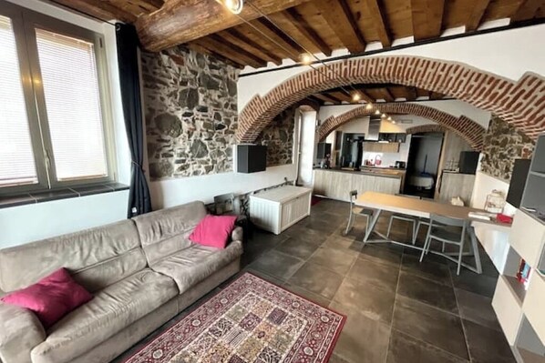 A cozy living area with a sofa, a patterned rug, and a stone wall. - Seafront Apartment in Sestri Levante - Sailorsistershouse (Sestri Levante)