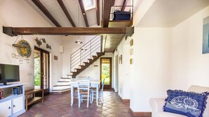 Un amplio salón con una mesa de comedor, sillas, un sofá y un televisor.