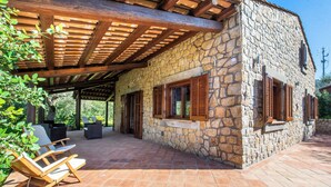 Un edificio de piedra con un patio techado, muebles de madera y un muro de piedra.