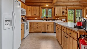 Eine Küche mit Holzausstattung, einem weißen Kühlschrank, einer Mikrowelle und einem Spülbecken.