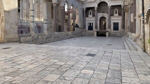 Ein Innenhof mit Steinpflasterung und klassischer Architektur, darunter Säulen und Bögen.