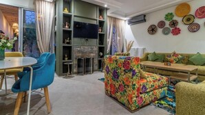 Un salon moderne avec un canapé, un téléviseur et un coin repas comprenant des chaises et une table.