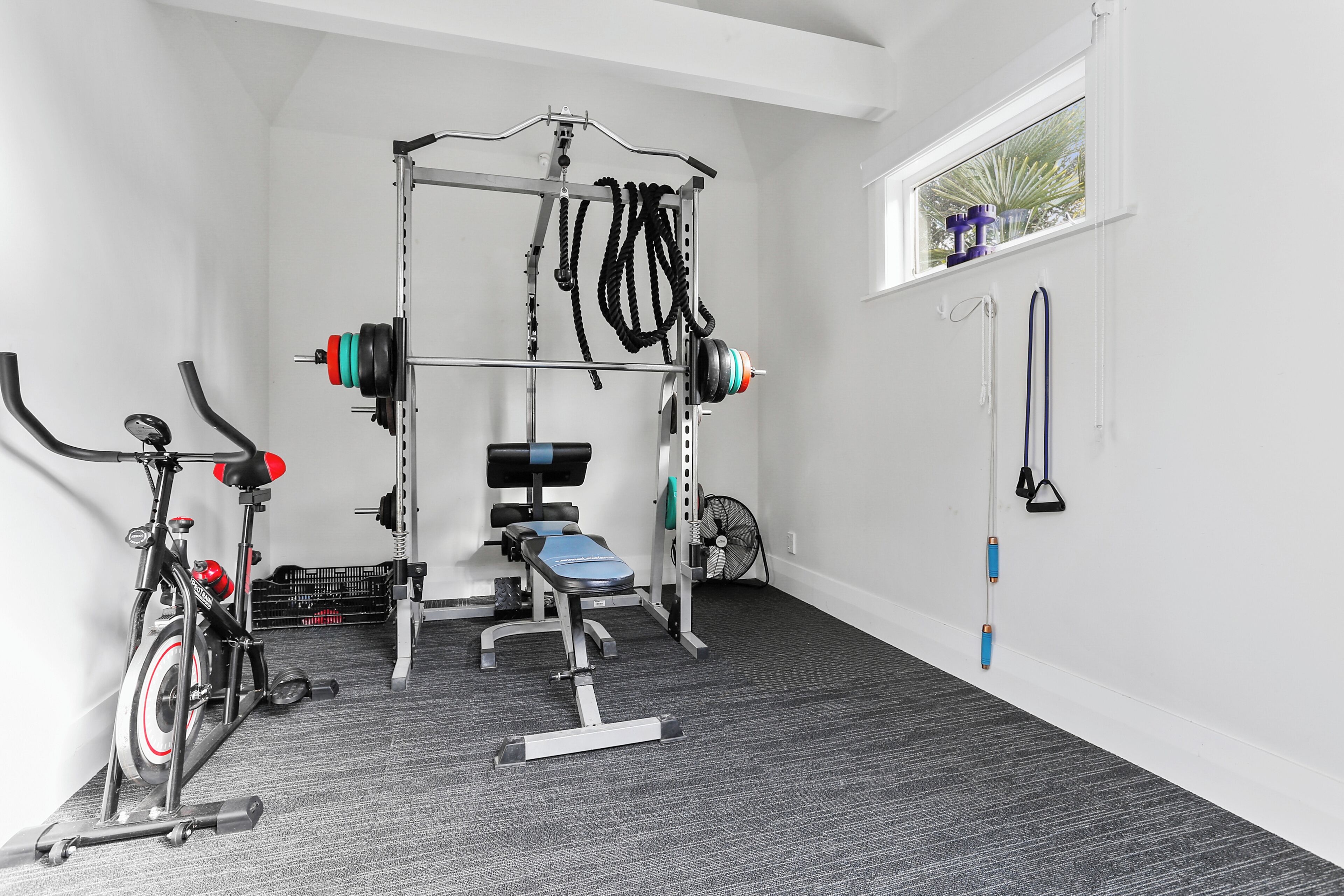 A gym with a stationary bike, weight bench, and various exercise equipment.