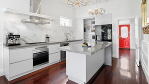 A modern kitchen with a central island, built-in oven, and stainless steel appliances.