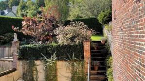 A brick staircase leading to a garden area with a variety of plants and a statue.