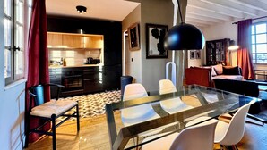 A modern kitchen with wooden cabinets and a dining area with a glass table and white chairs.