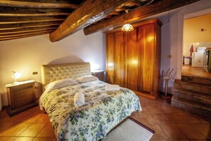 Ein Schlafzimmer mit Bett, Holzschrank, Nachttisch und Lampe.