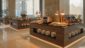 A modern buffet setup with multiple serving stations, a polished floor, and large windows allowing natural light. - Centre Point Danang Hotel & Residence (Da Nang)
