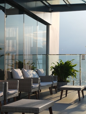 A balcony with wicker furniture, a potted plant, and a view of the cityscape. - Centre Point Danang Hotel & Residence (Da Nang)