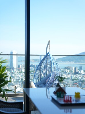 Una silla colgante con vistas a un paisaje urbano a través de un ventanal amplio.