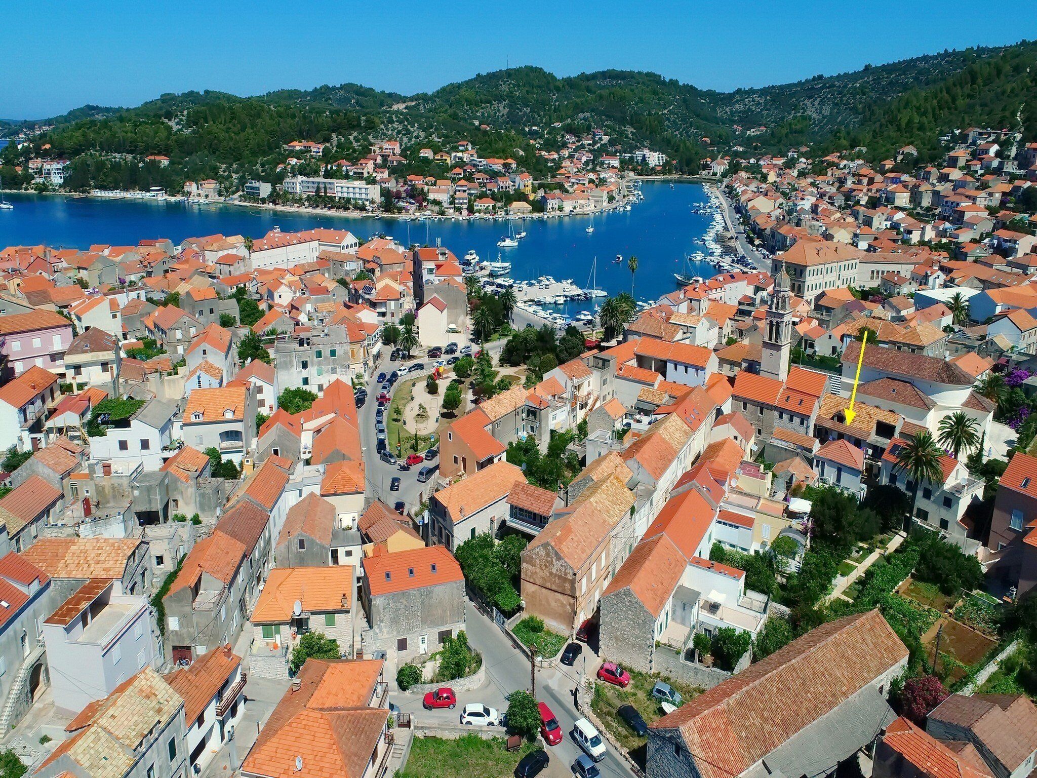 Un pueblo costero con tejados rojos, calles estrechas y un puerto deportivo lleno de barcos.