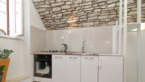 A kitchen with a stone ceiling, white cabinets, a built-in oven, and a sink. - Studio Joković (Vela Luka)
