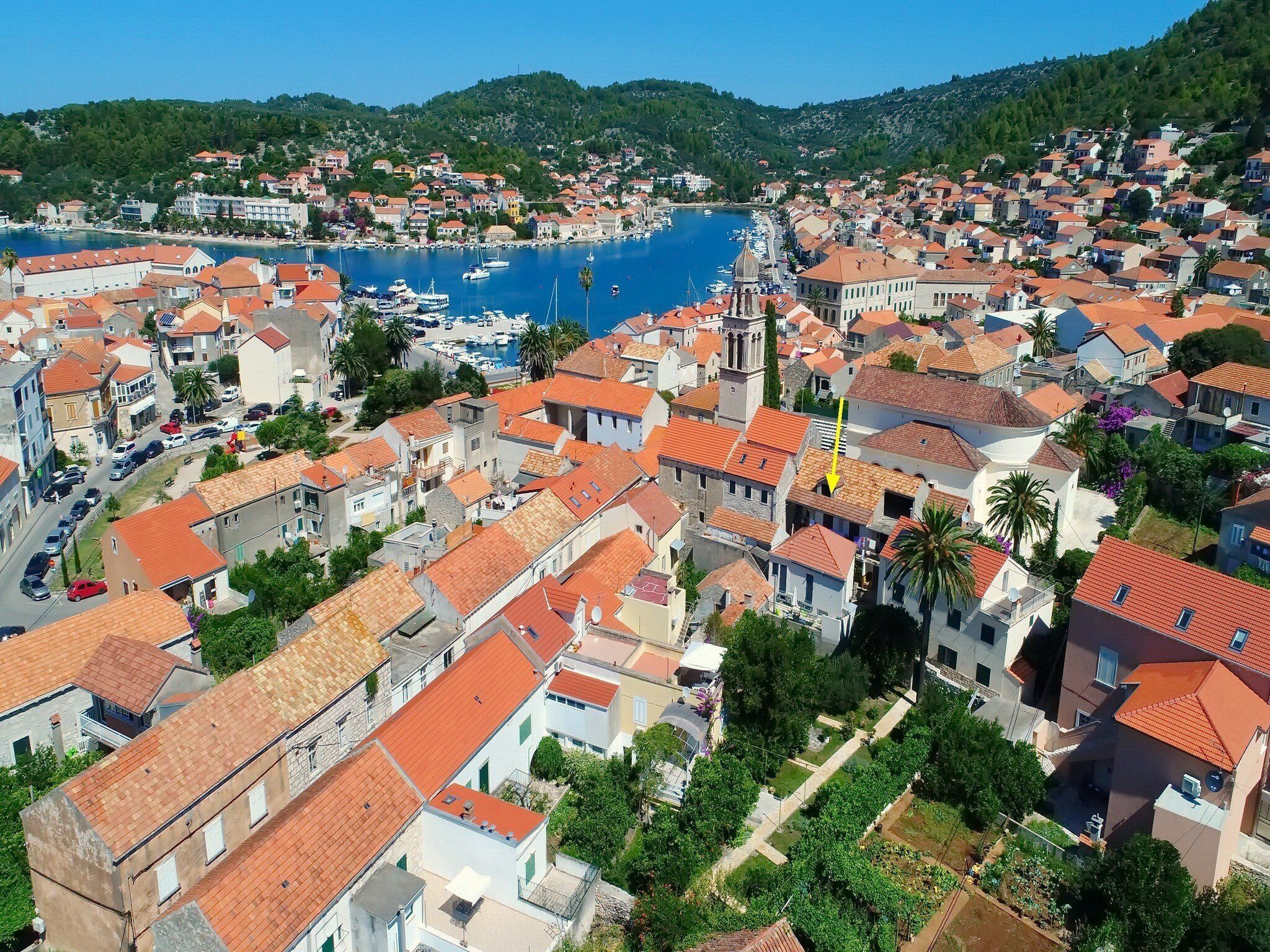 A coastal town with red-roofed buildings, a marina, and a church.