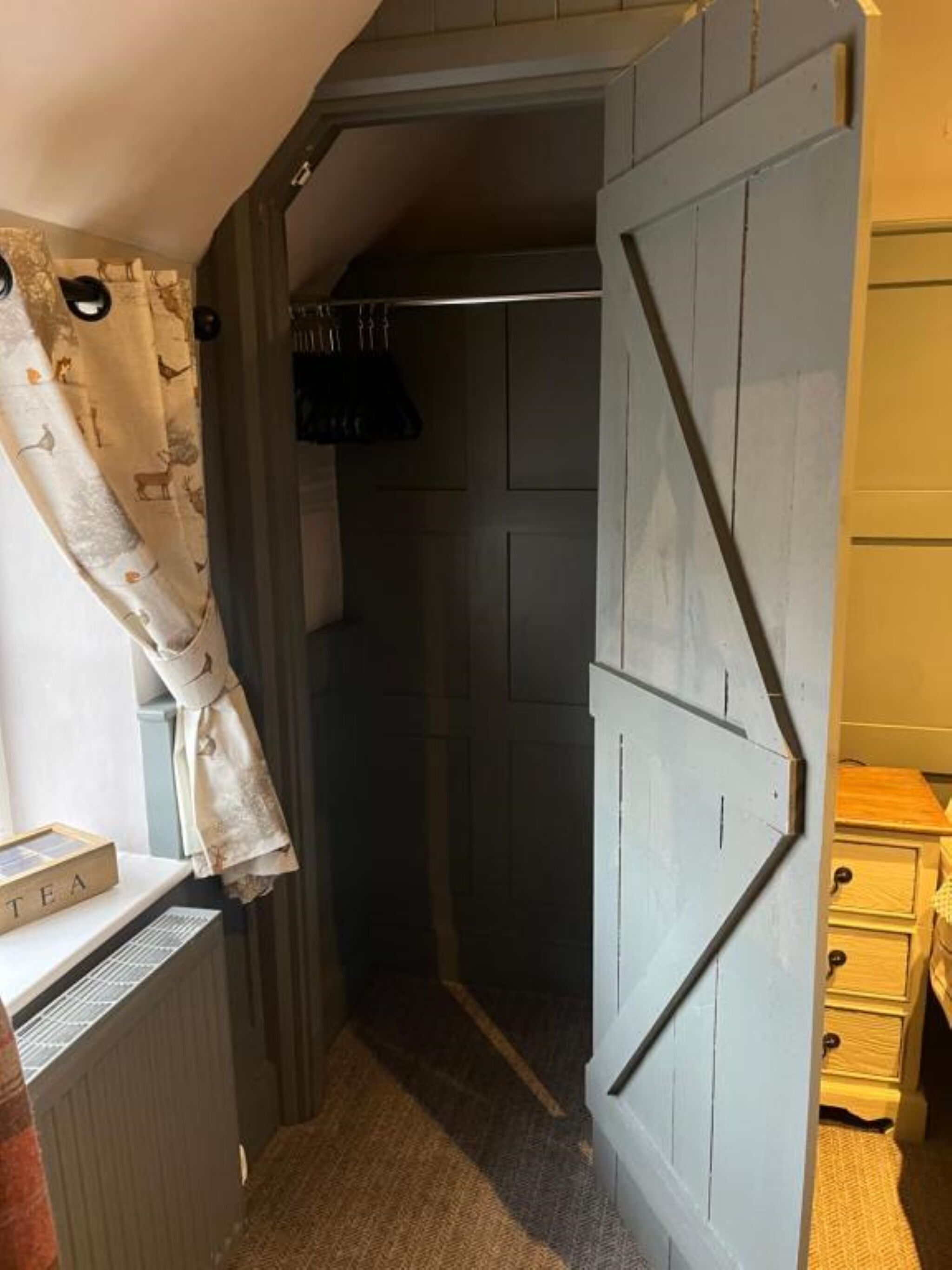 Un pasillo estrecho con una puerta de madera, un radiador y una pequeña mesa con una caja etiquetada 