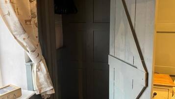 Un pasillo estrecho con una puerta de madera, un radiador y una pequeña mesa con una caja etiquetada