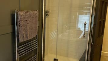 Ein Badezimmer mit einer gläsernen Duschkabine, einer weißen Badewanne und Holzboden.