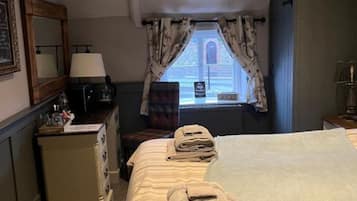 A hotel room with a bed, a desk, a mirror, and a window with curtains.