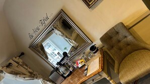 A room with a vanity table, a mirror, a chair, and a window with curtains. - The Crown Inn (King's Lynn)