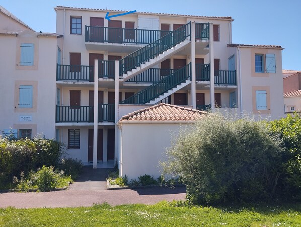 A multi-story building with balconies, a staircase, and a sign reading 'LA POINTE DU LAC'.