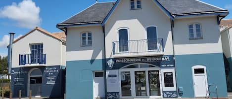 A two-story building with a sign for 'POISSONNERIE DE BOURGENAY' and a smaller adjacent building labeled 'Donnazurra Pizzeria Restaurante Bar'.