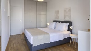 Et soveværelse med seng, natbord, lampe, garderobeskab og et billede på væggen.