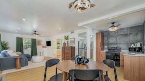 Un salon moderne comprenant une table à manger, des chaises et un canapé. Il y a également un coin cuisine avec une cuisinière, un four et un réfrigérateur.