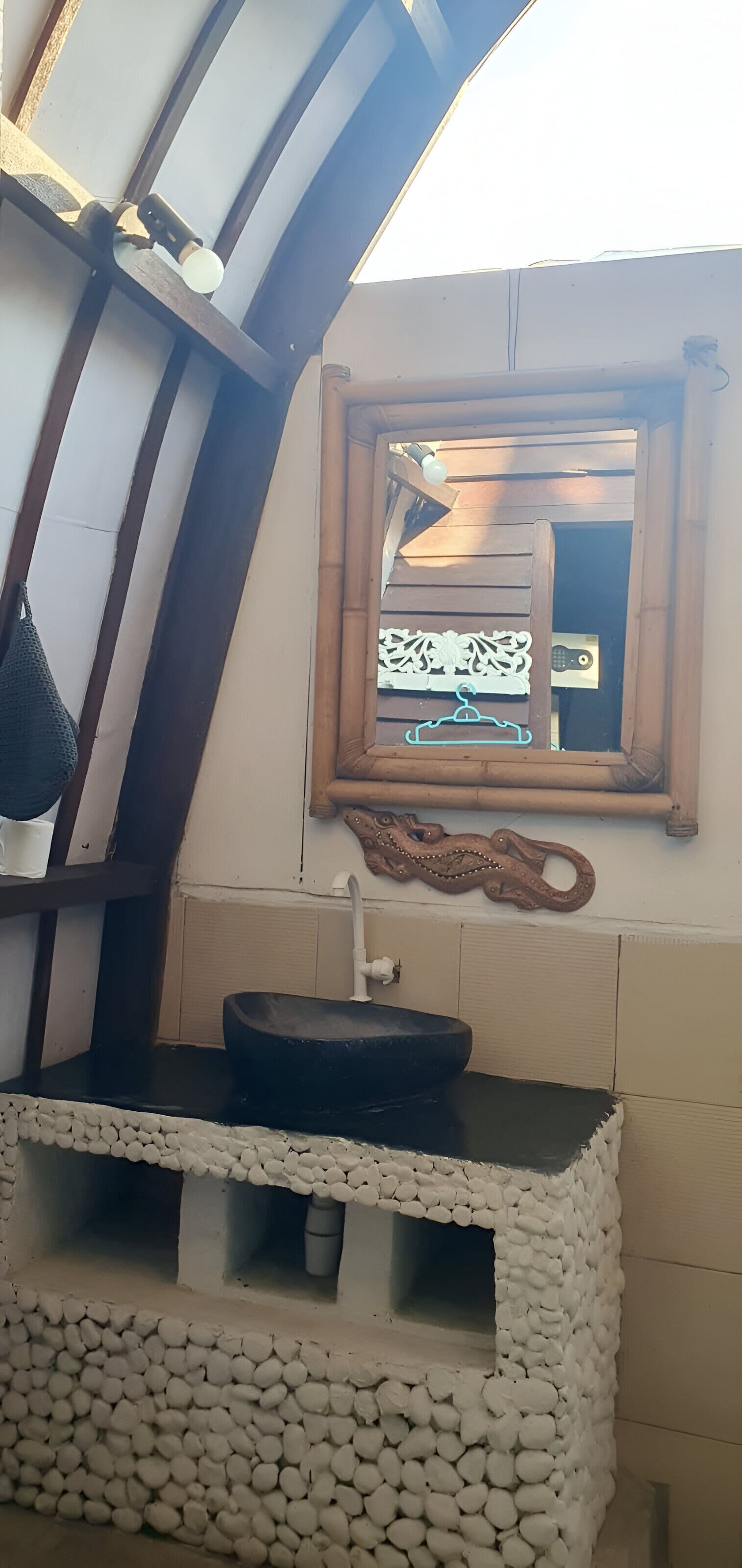 Une salle de bain avec un lavabo noir, une étagère en bois et un miroir.