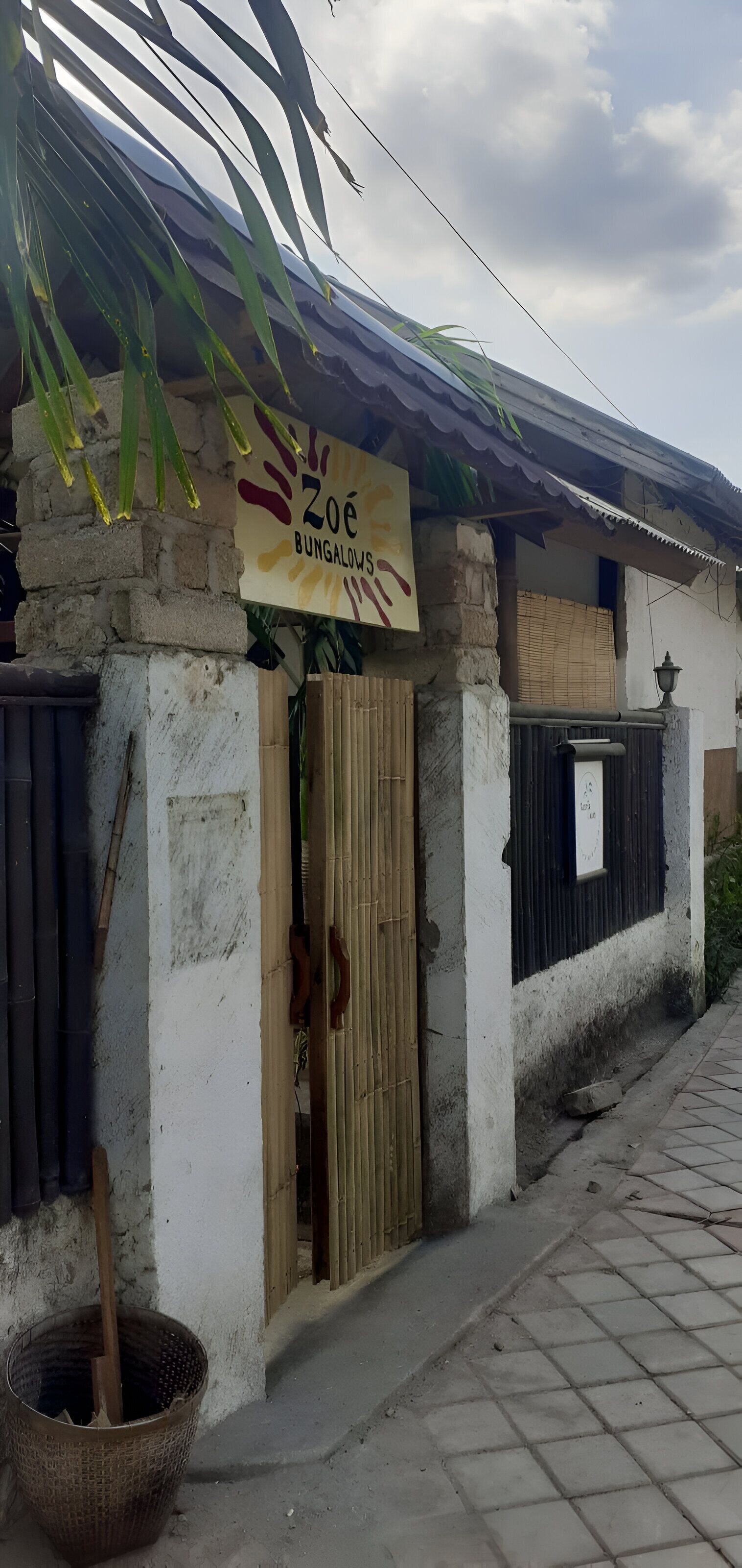 Un bâtiment sur lequel on peut lire l’inscription « Zoé BUNGALOWS », et une porte en bambou.