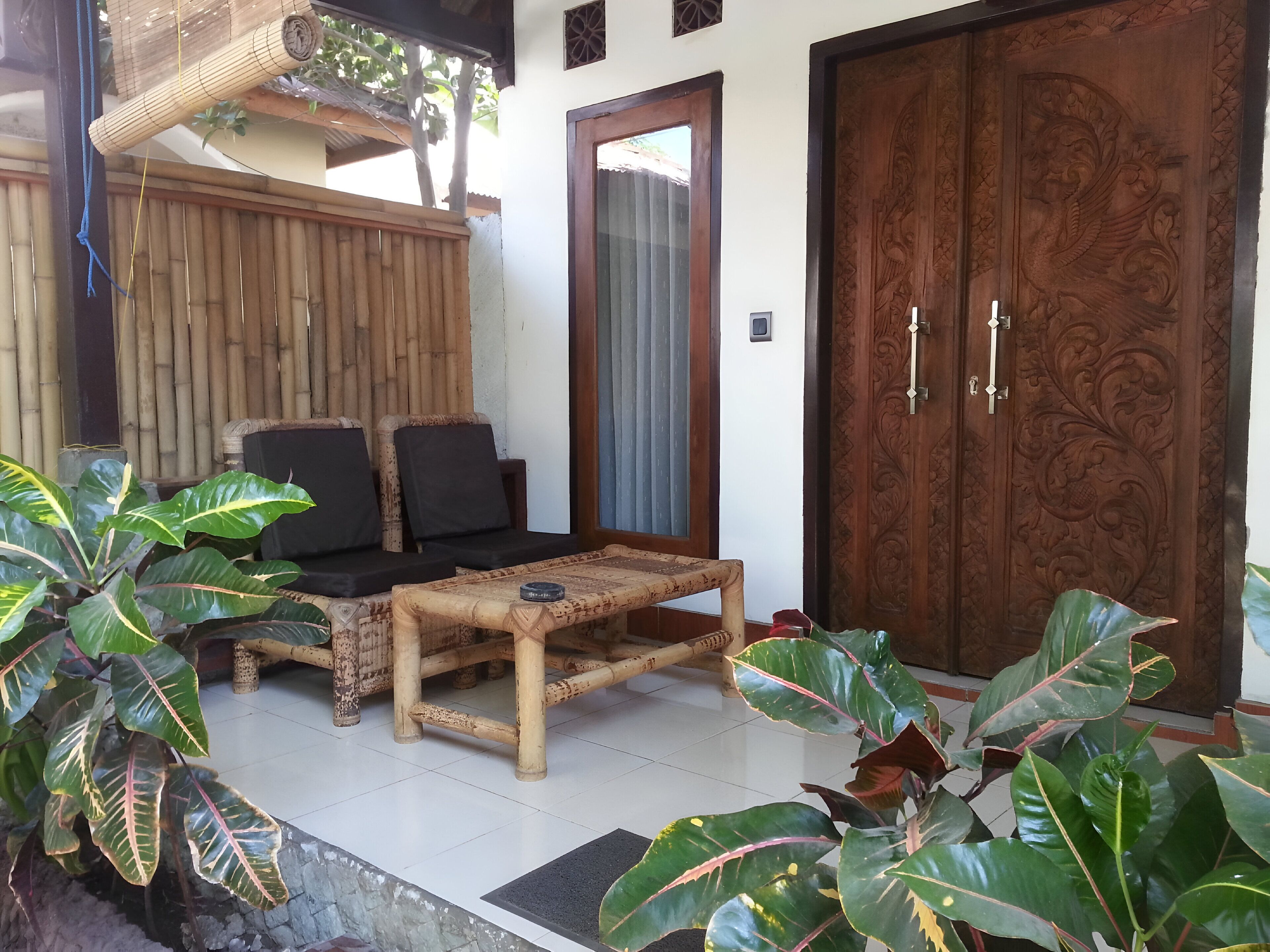 A room with a wooden sofa, a small table, and a large door with intricate carvings.