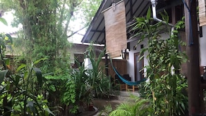 Un patio con una hamaca, plantas en macetas y piso de baldosas.