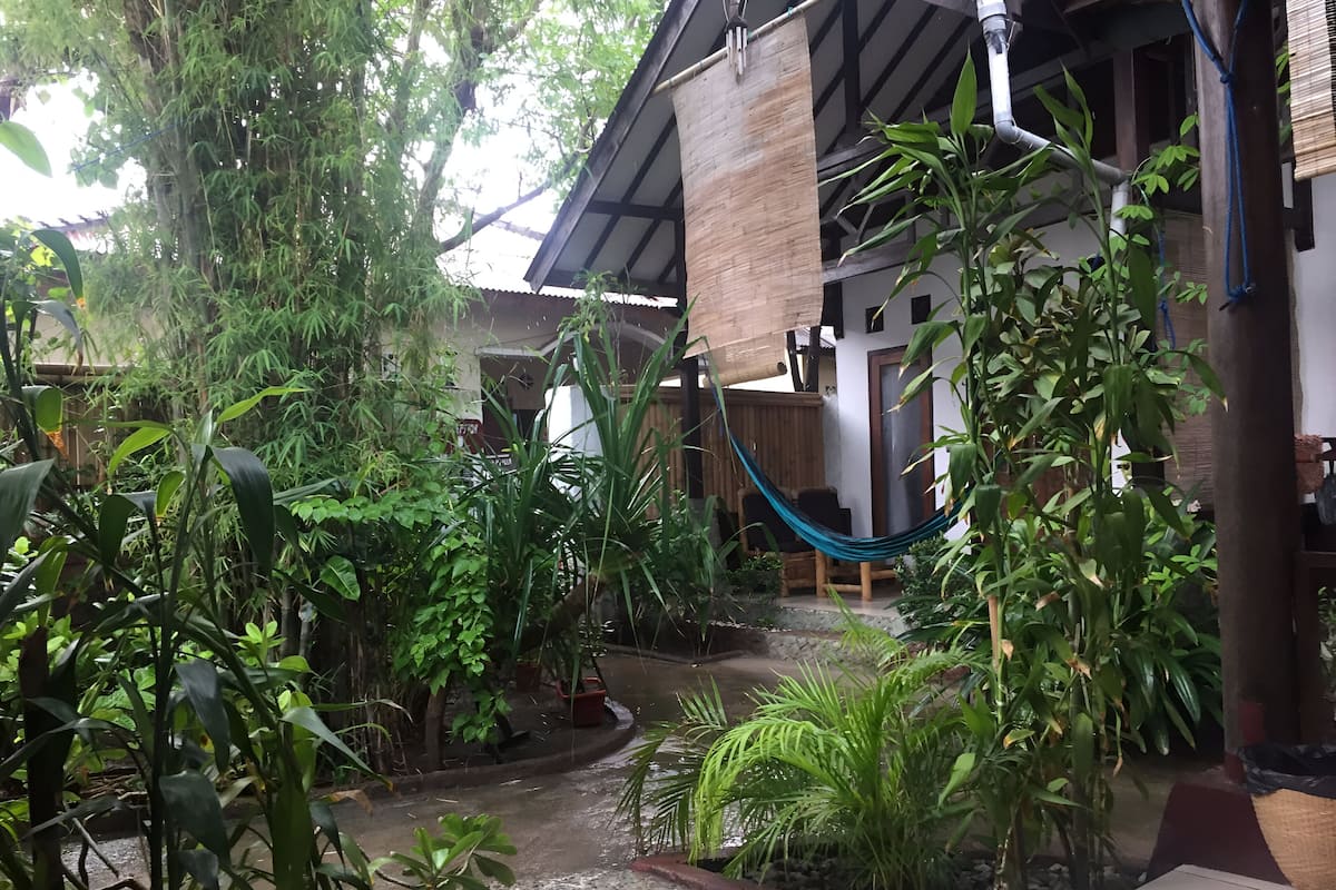 A courtyard with a hammock, potted plants, and a tiled floor.