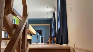 A staircase leading to a room with a blue wall, a wooden floor, and a window with curtains. - Complete apartment, 4 sleeping areas for up to 8 people (Bielefeld)