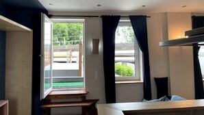 A room with a large window, a wooden bench, a bed, and a small table. - Complete apartment, 4 sleeping areas for up to 8 people (Bielefeld)